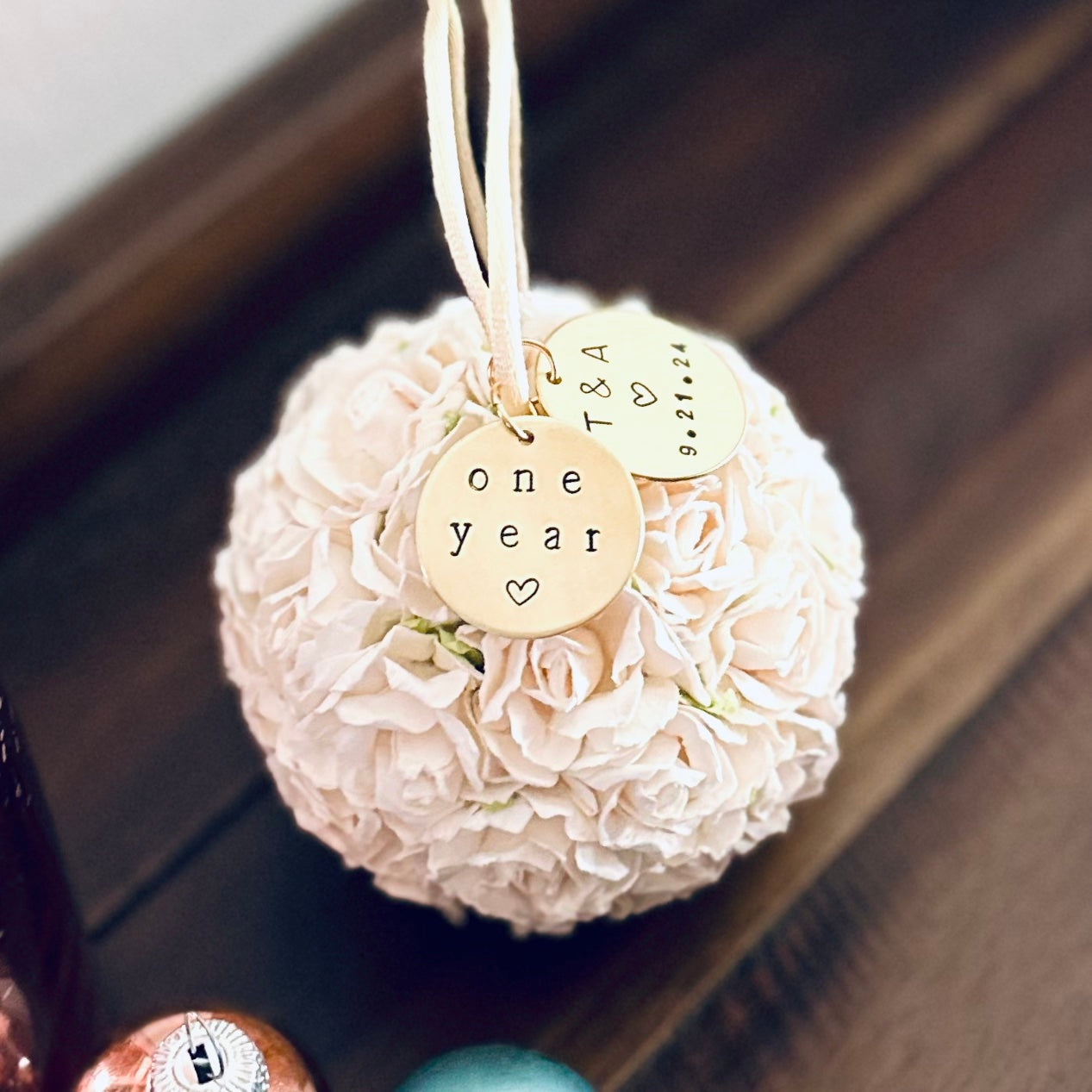white flower ball ornament with a "one year" charm attached. Suggests a 1st anniversary paper-theme gift.