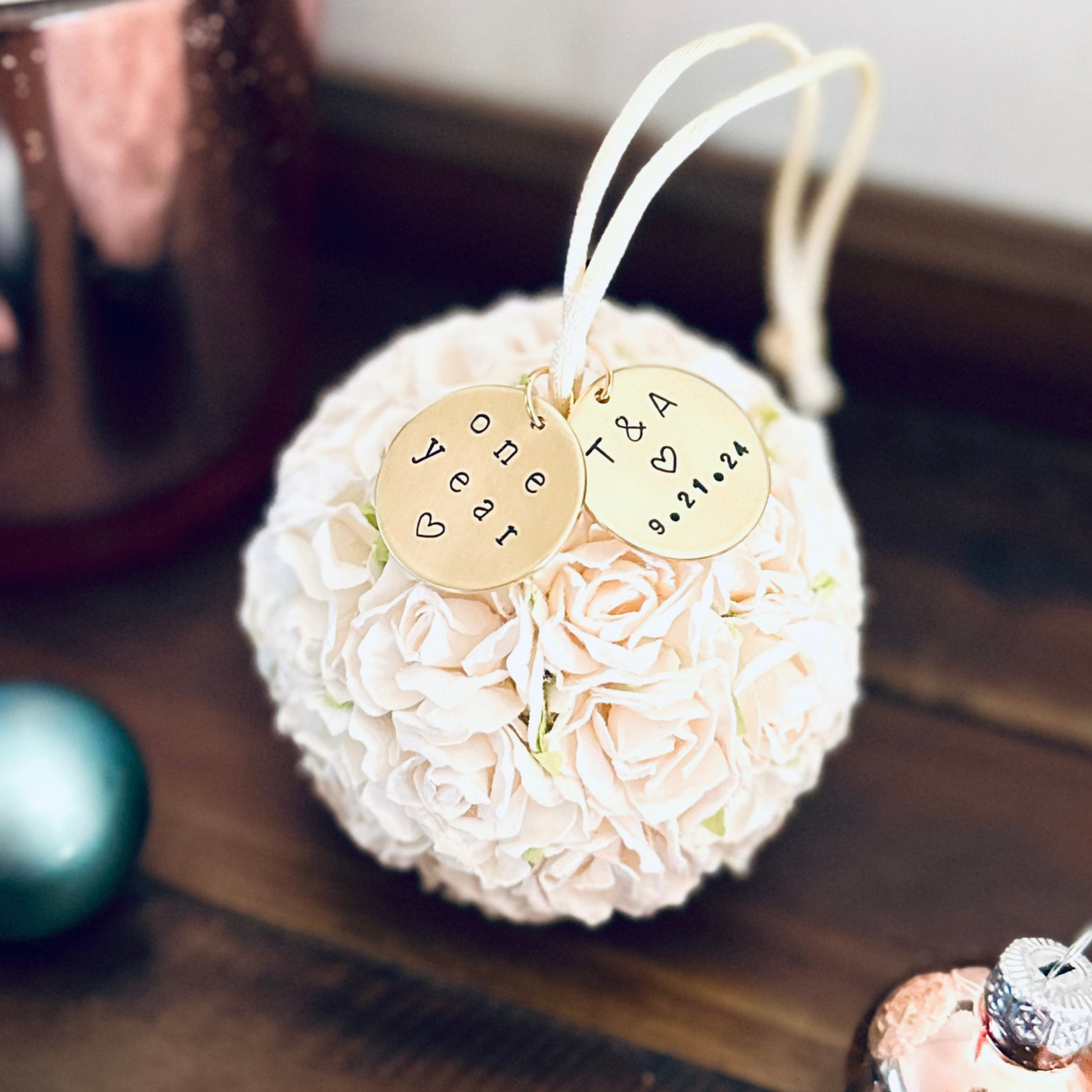 Decorative first anniversary ornament with personalized gold charms on a wooden surface
