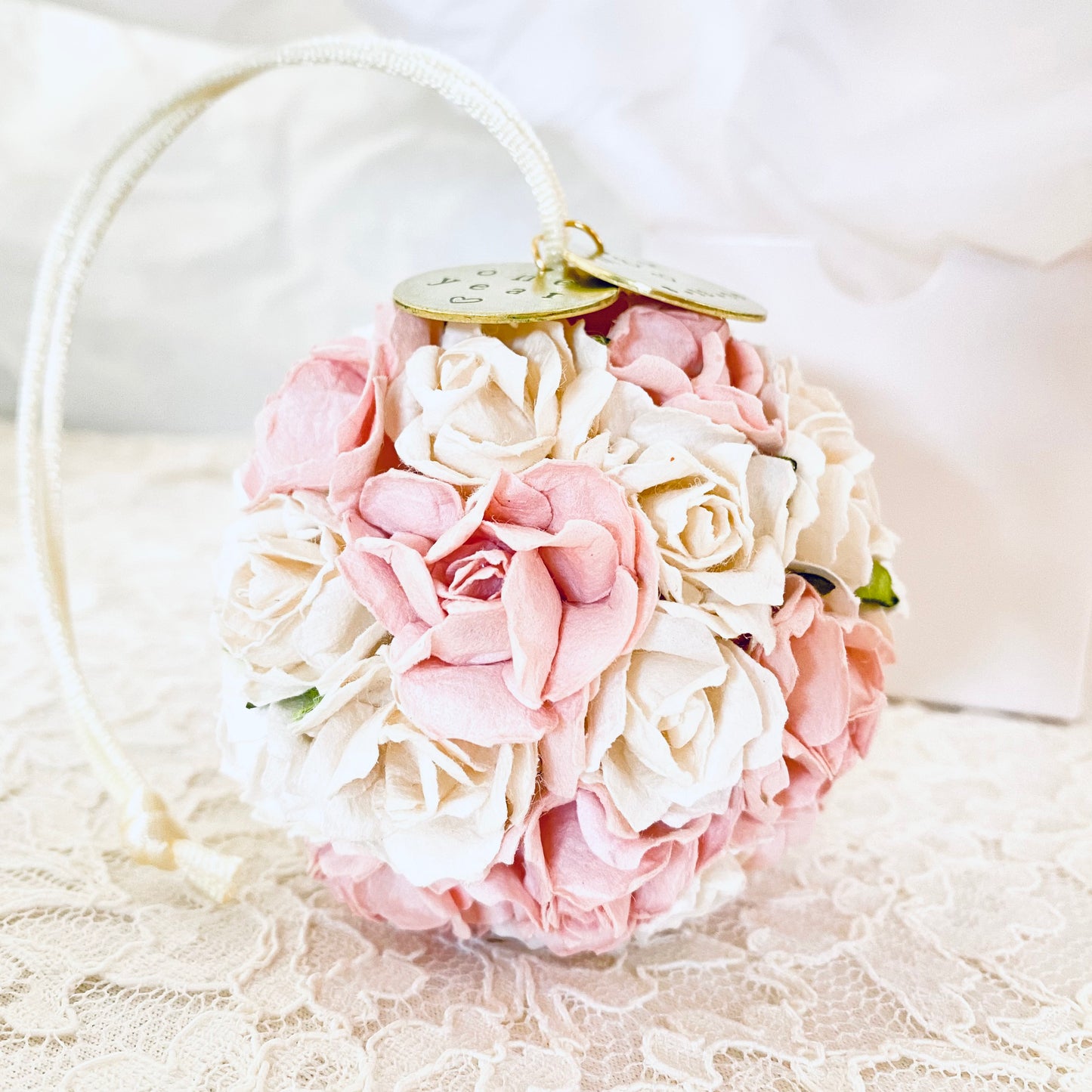 a blush pink and white flower ball ornament with two personalized charms.