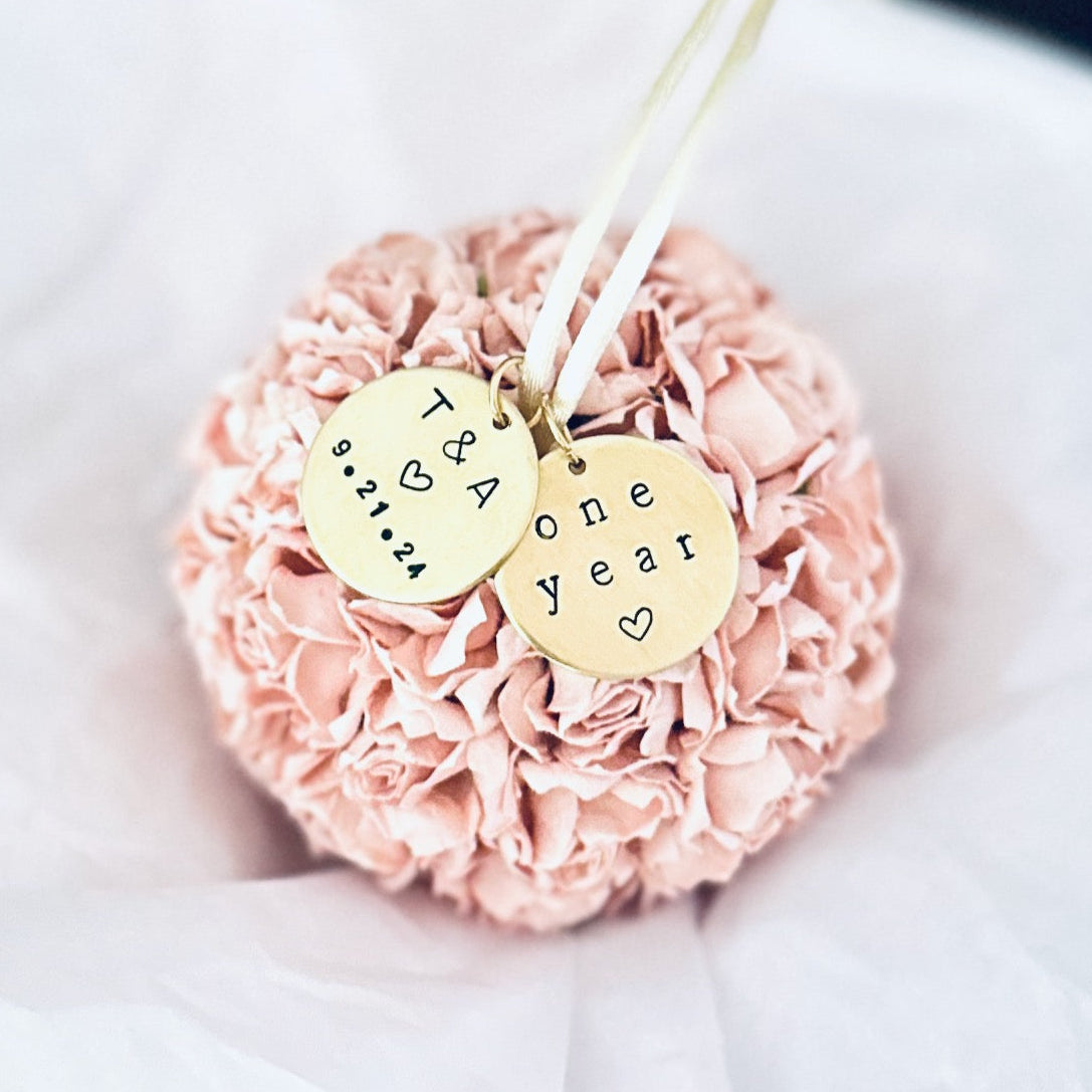 a blush pink flower ball ornament to celebrate a 1st wedding anniversary. The one year anniversary theme of Paper is represented with 40 paper flowers, formed into a perfect ball . The ornament has 2 personalized charms attached to a satin hanger. One reads "One Year" with a small heart, the other is custom engraved with a couples' initials and wedding date.