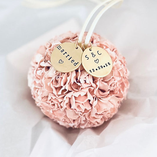 Pink flower ball-shaped ornament with 'married' and personalized gold tags on a white background