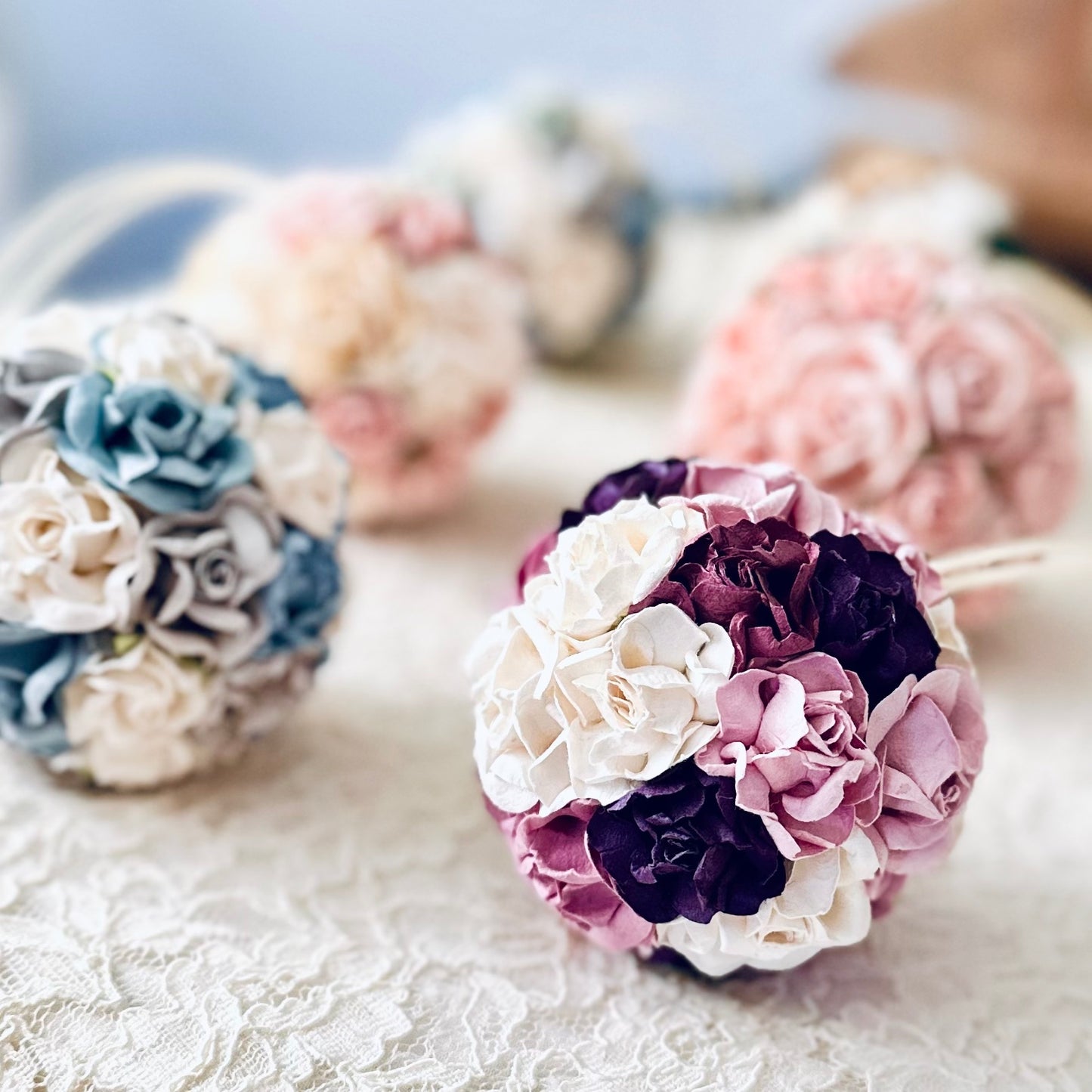 Custom flower ball ornaments in various colors on a textured surface.