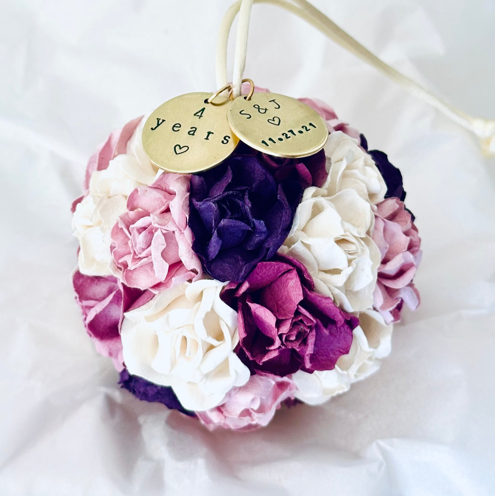 4 year anniversary flower ornament with gold charms on a white background.  Flowers are in shades of plum, purple, wisteria, lavender, and white.